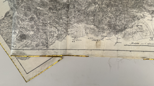 Detailansicht des zerstörten Goldrandes und des ausfransenden Stoffes, Abbildung einer Küstenregion