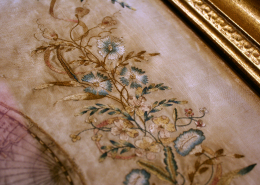 Detailaufnahme der dekorativen Elemente: obere Randverzierung aus gestickten Blättern und Blüten (Kornblumen)