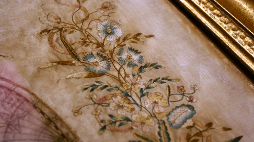 Detailaufnahme der dekorativen Elemente: obere Randverzierung aus gestickten Blättern und Blüten (Kornblumen)