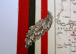 Detailaufnahme des rot-schwarzen Randes, verziert mit Eichenblättern